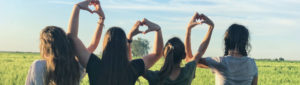 group of young girls looking out at bright day and making hearts with their arms